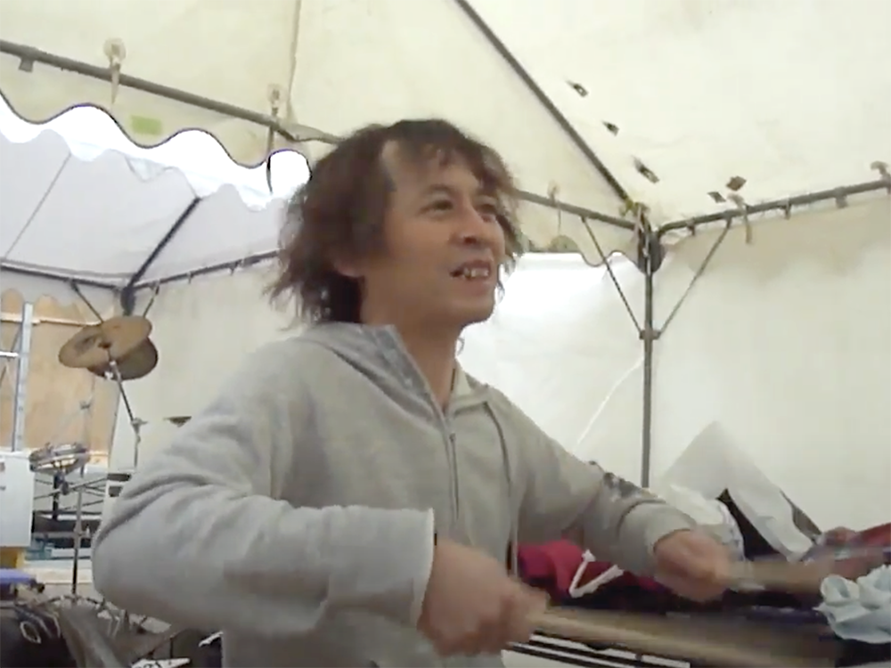 テントでドラムの練習をする男性